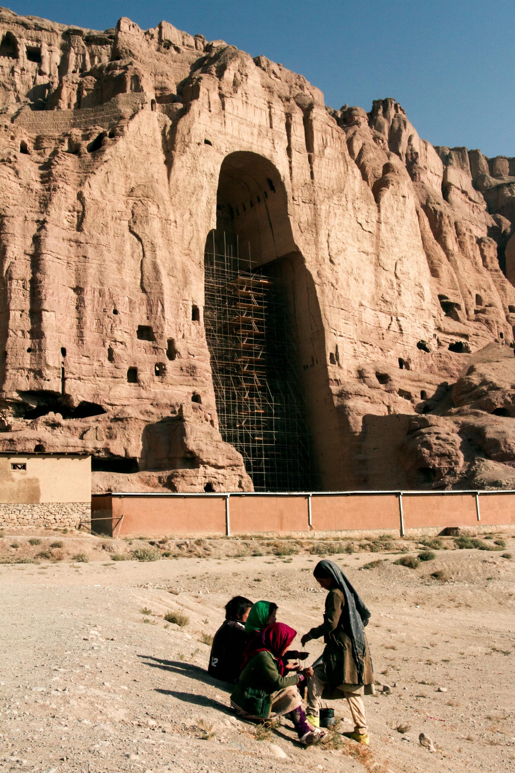 Historic Bamyan cliff with colossal Buddha niches and local children in Afghanistan.